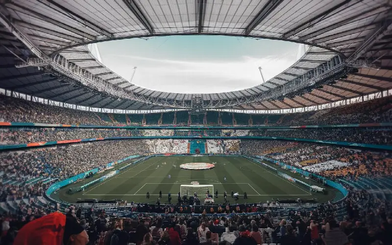 Tribunes pleines d'un grand stade de football couvert, vues depuis le haut des gradins