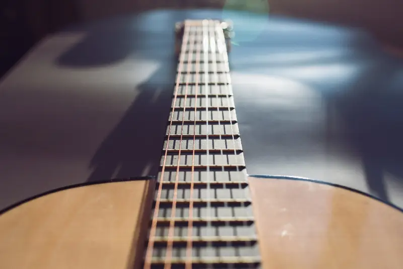 Manche d'une guitare classique vu depuis la caisse, cordes et frettes au soleil