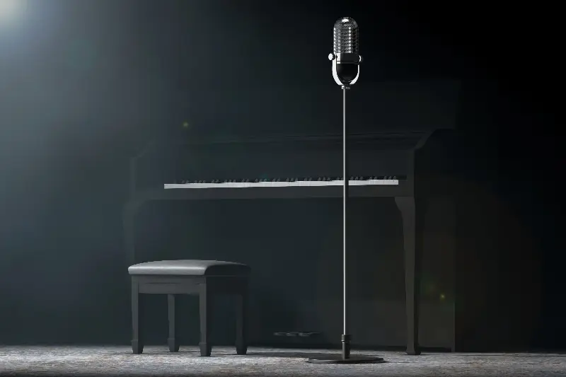Piano droit noir et micro sur pied sur une scène sombre, sous un projecteur