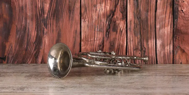 Une trompette ancienne argentée posée sur une table en bois