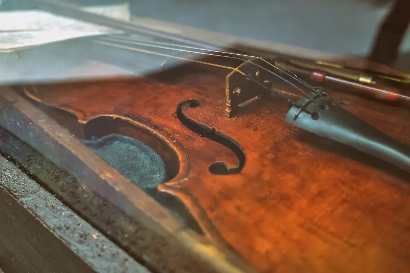 Violon ancien au vernis usé couché dans son étui, vu de près autour de l'ouïe et du chevalet